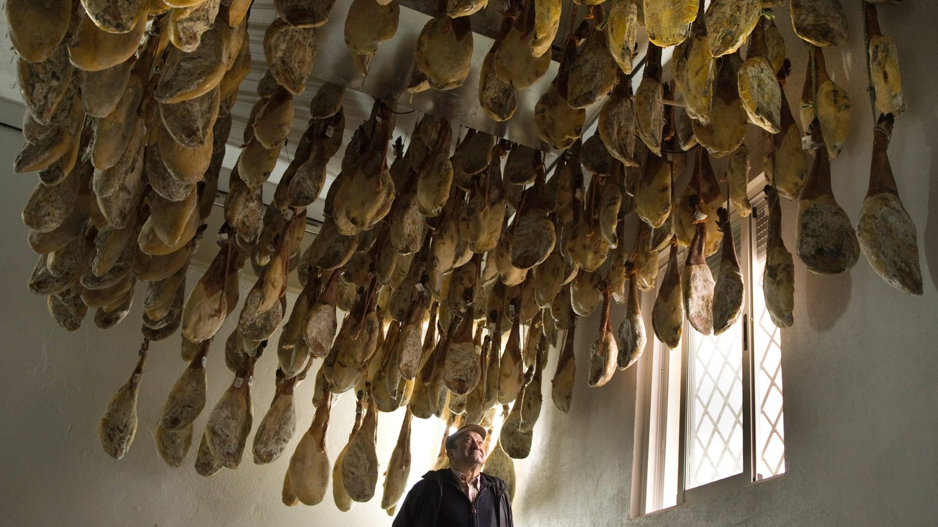 Faustino Prieto, owner of a familyrun business near Salamanca, is dwarfed by legs of dry-cured jamón ibérico de bellota. Photo: Denis Doyle/Getty