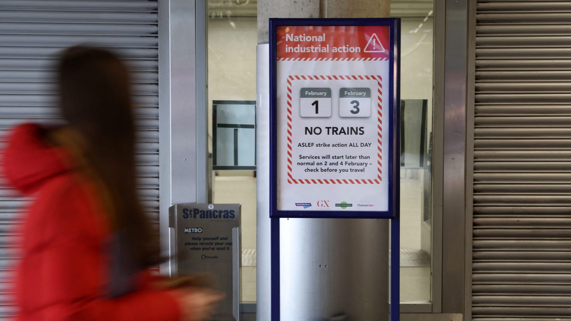 A commuter walks past a board informing passengers of this week's rail strike at Saint Pancras train station in London on February 3 (Photo by ISABEL INFANTES/AFP via Getty Images)