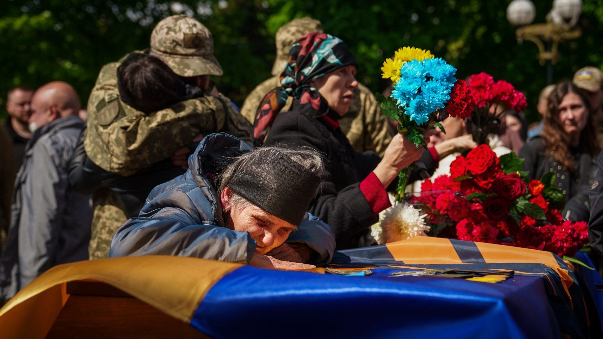 An elderly woman cries over the coffin of Ukrainian serviceman Valerii Sosnovskii who died near Bakhmut, Donetsk region, during his funeral ceremony in Poltava (Photo by IHOR TKACHOV/AFP via Getty Images)