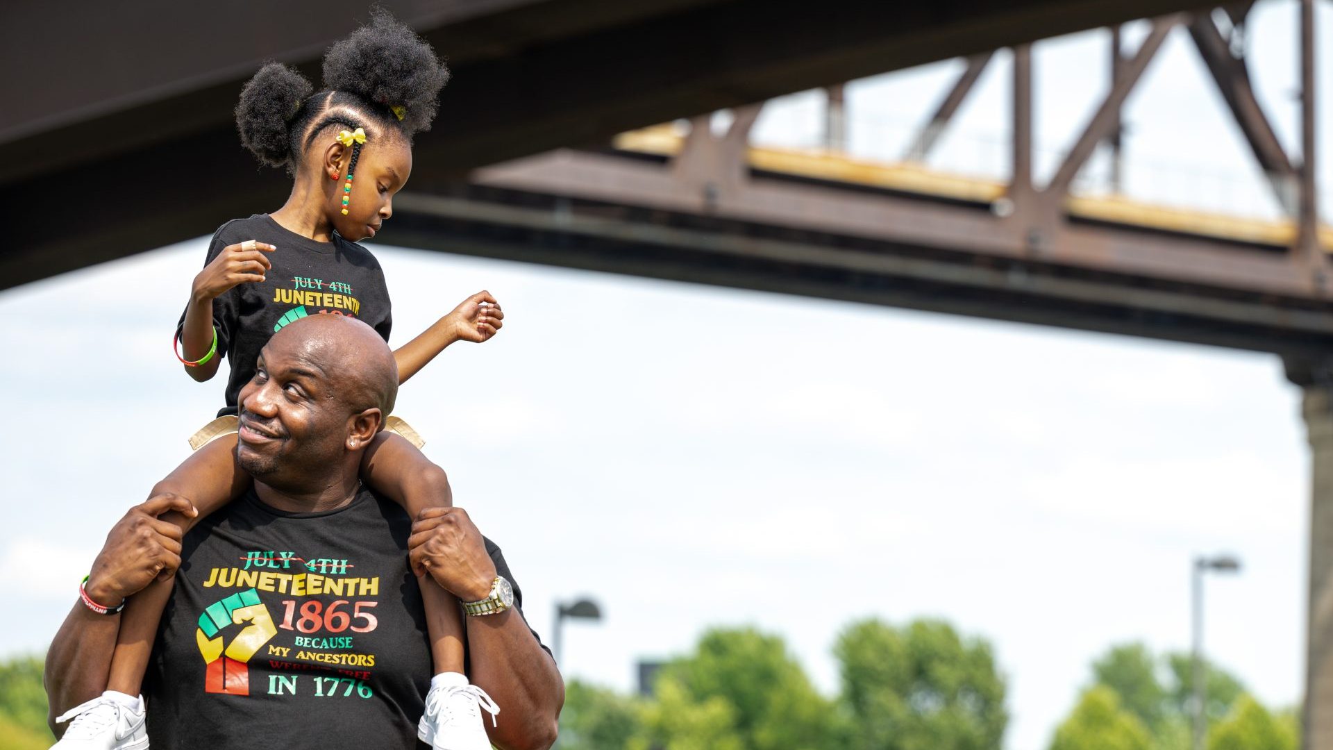  A young girl sits on a man's shoulders during the Louisville Juneteenth Festival. Photo: 