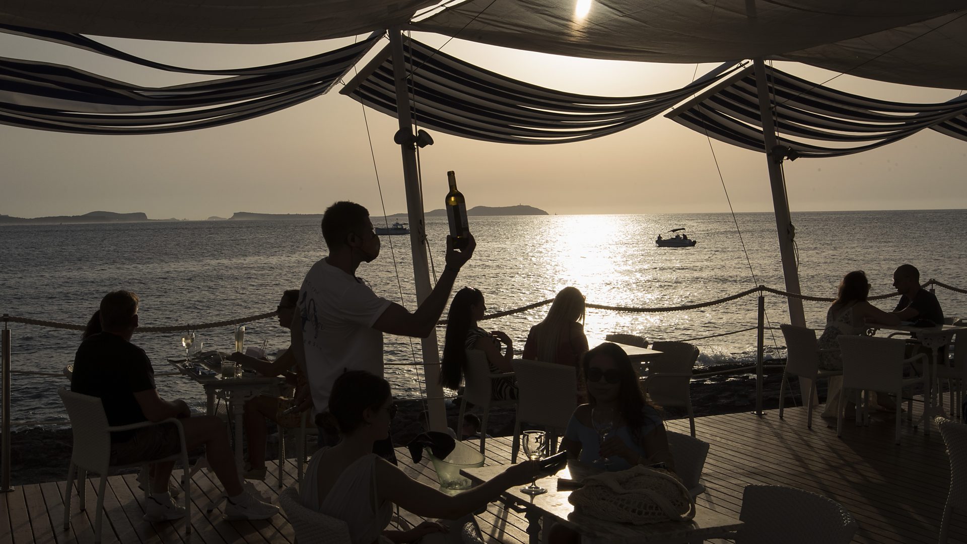 Tourists sit at the terrace bar "Cafe del Mar" in Sant Antoni de Portmany, Ibiza, on July 30, 2020. Photo: JAIME REINA/AFP via Getty Images