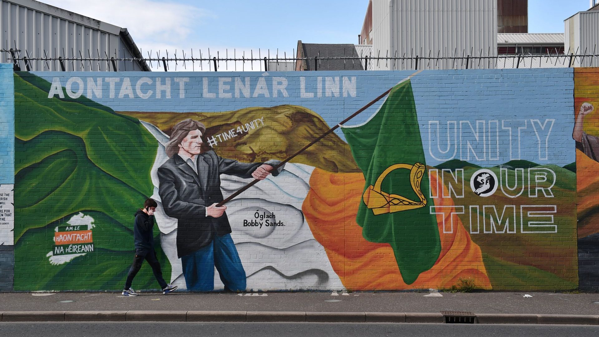 A man walks past a Sinn Féin mural in Belfast calling for Am le hAontacht na hÉireann – Time for unity of Ireland.. Photo: Charles McQuillan/Getty