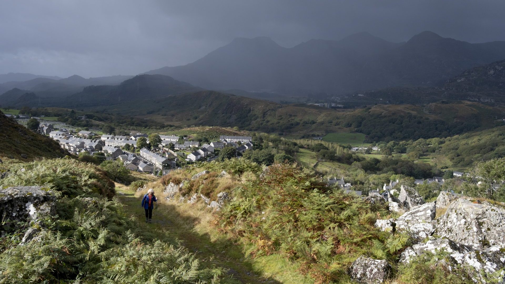 With dark skies approaching over distant mountains, a walker climbs a public footpath, once an industrial track for the slate mining industry. Photo: Richard Baker / In Pictures via Getty Images