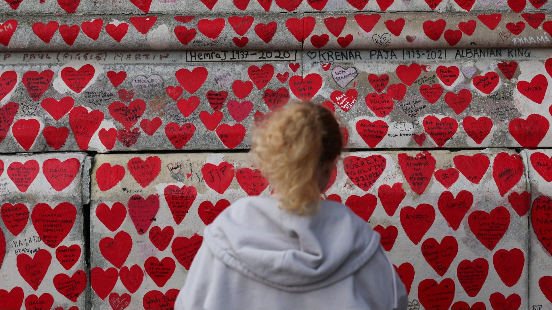 A person looks at messages and hearts on the National Covid Memorial Wall. Photo: DANIEL LEAL/AFP via Getty Images 