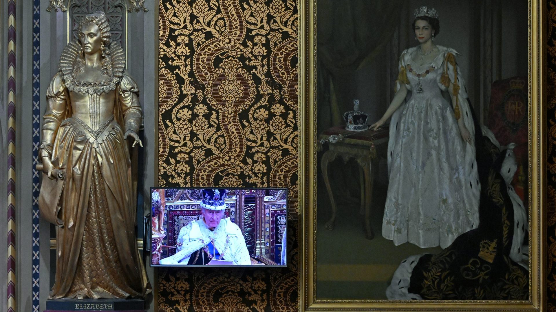 A television screen, alongside a painting of the Late Queen Elizabeth II, displays footage of King Charles III reading the King's Speech, in the Royal Gallery during the State Opening of Parliament (Photo by Justin Tallis - WPA Pool/Getty Images)
