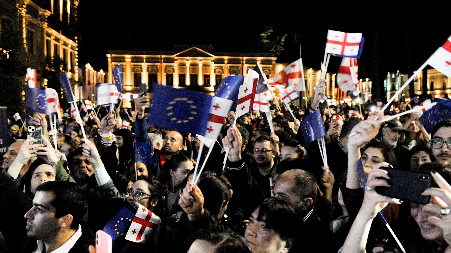 People gather and hold Georgian and European flags in front of the presidential palace celebrating the European Commission decision. Photo: Nicolo Vincenzo Malvestuto/Getty Images