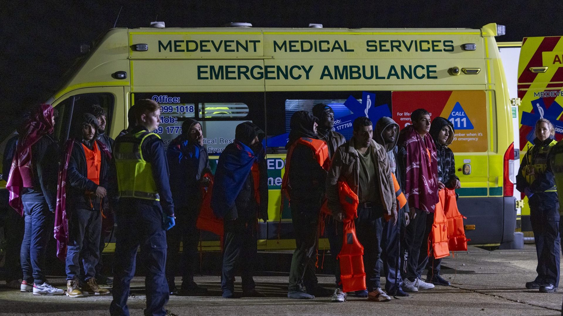 Coast Guard, Ambulance staff, Border Force and police escort asylum seekers who have just landed on Dungeness beach on an RNLI life boat late in the evening. Photo: Andrew Aitchison / In pictures via Getty Images