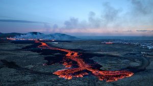 Lava explosions and billowing smoke are seen near residential buildings in the southwestern Icelandic town of Grindavik after a volcanic eruption. Photo: HALLDOR KOLBEINS/AFP via Getty Images