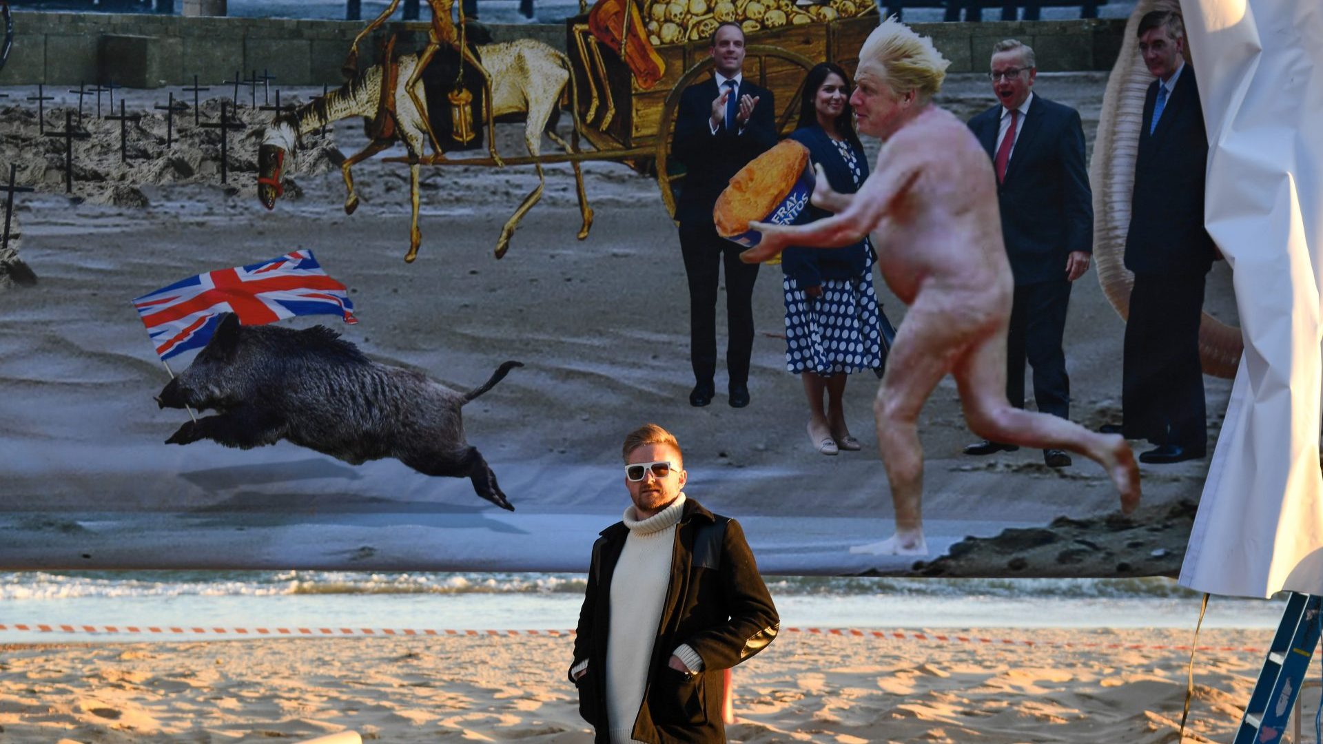 Christopher Spencer, aka: Cold War Steve poses in front of the censored artwork on Boscombe beach. Photo: Finnbarr Webster/Getty Images