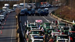 French farmers arrive in front of French CRS police officers standing beside French gendarmerie armoured personnel carriers near Chilly-Mazarin, south of Paris. Photo: EMMANUEL DUNAND/AFP via Getty Images