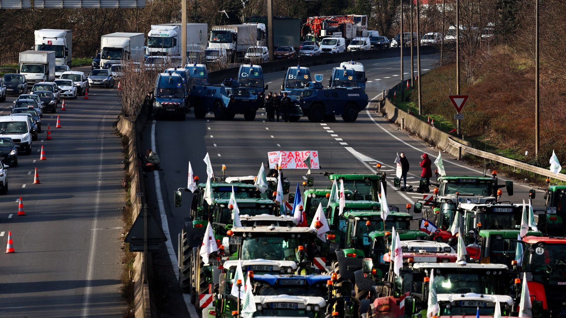 French farmers arrive in front of French CRS police officers standing beside French gendarmerie armoured personnel carriers near Chilly-Mazarin, south of Paris. Photo: EMMANUEL DUNAND/AFP via Getty Images