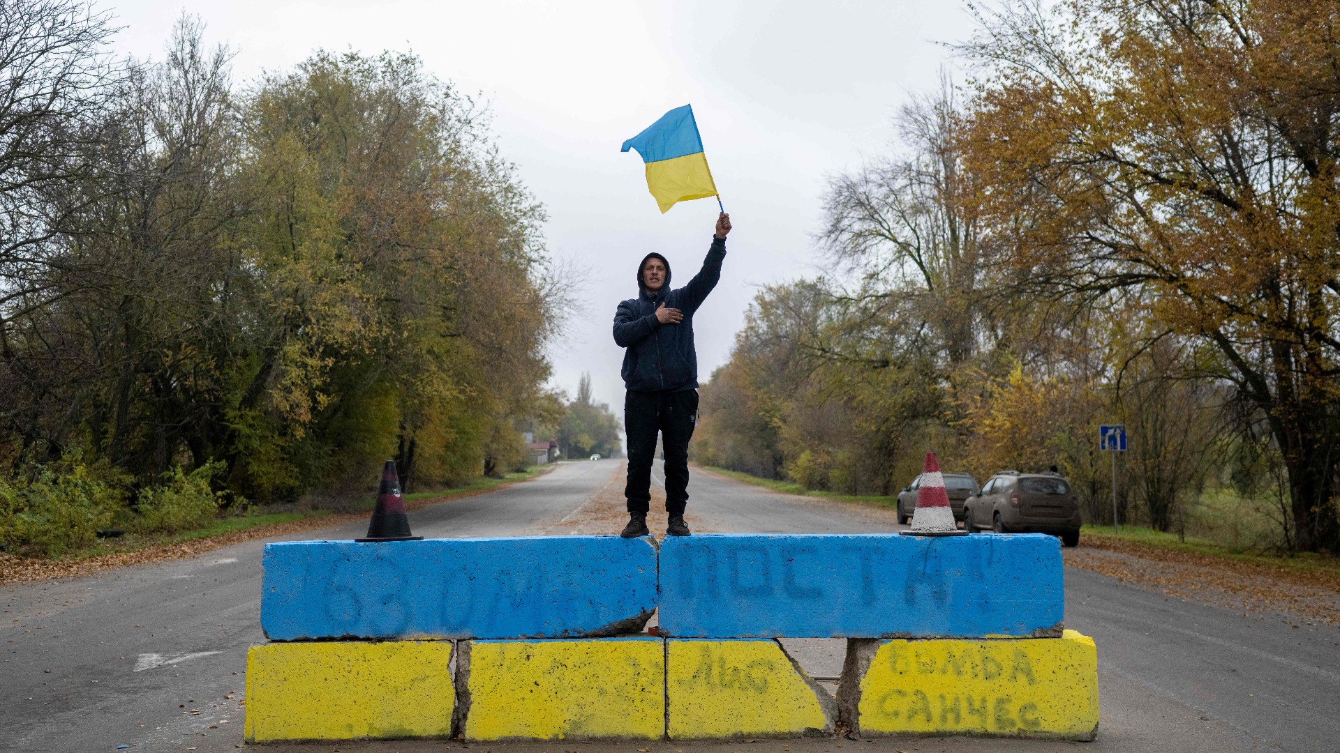 A resident of Kherson celebrates the liberation of the city in November 2022 at a former Russian checkpoint. Photos: Bulent Kilic/AFP/Getty