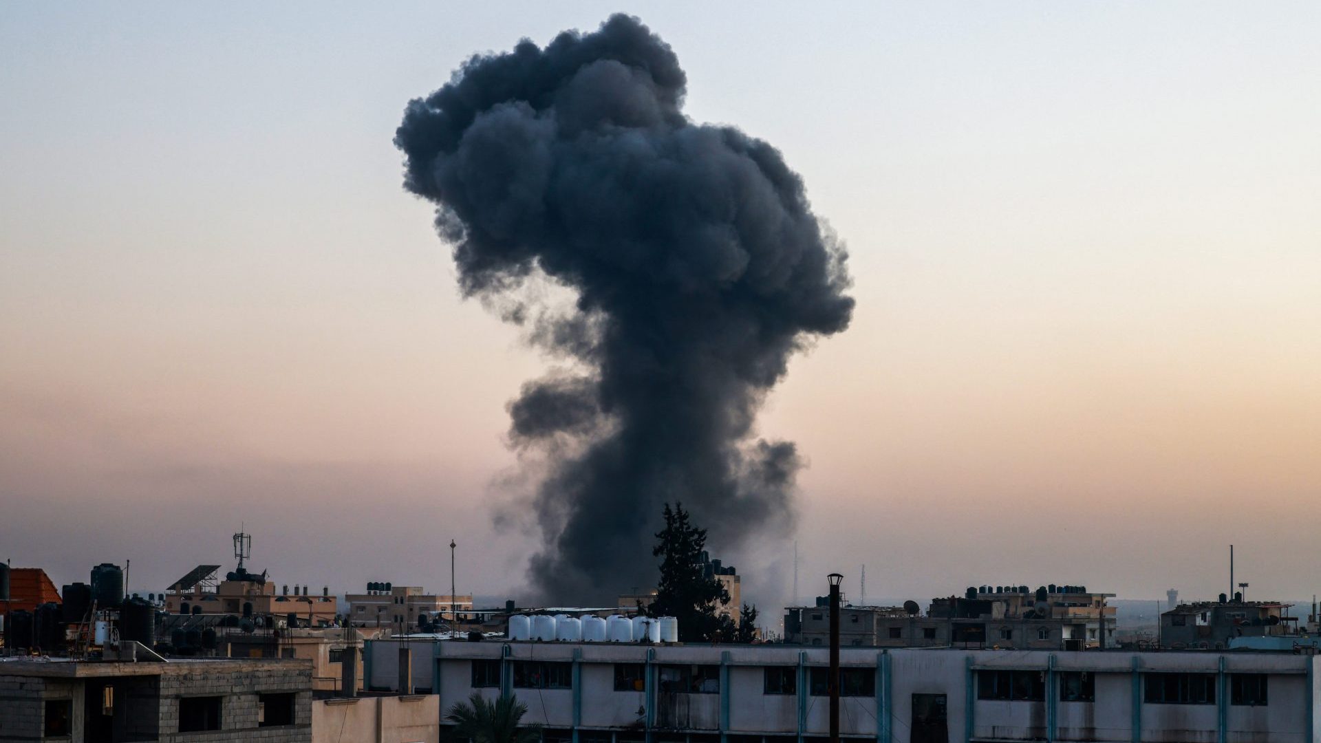 A billow of smoke rises over buildings after an Israeli strike in Rafah (Photo by MOHAMMED ABED/AFP via Getty Images)