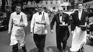 July 1955: Italian waiters in training for their annual race; carrying a half bottle of wine all the way from Soho Square to Greek Street without spilling a drop. Photo: Reg Speller/Fox Photos/Getty