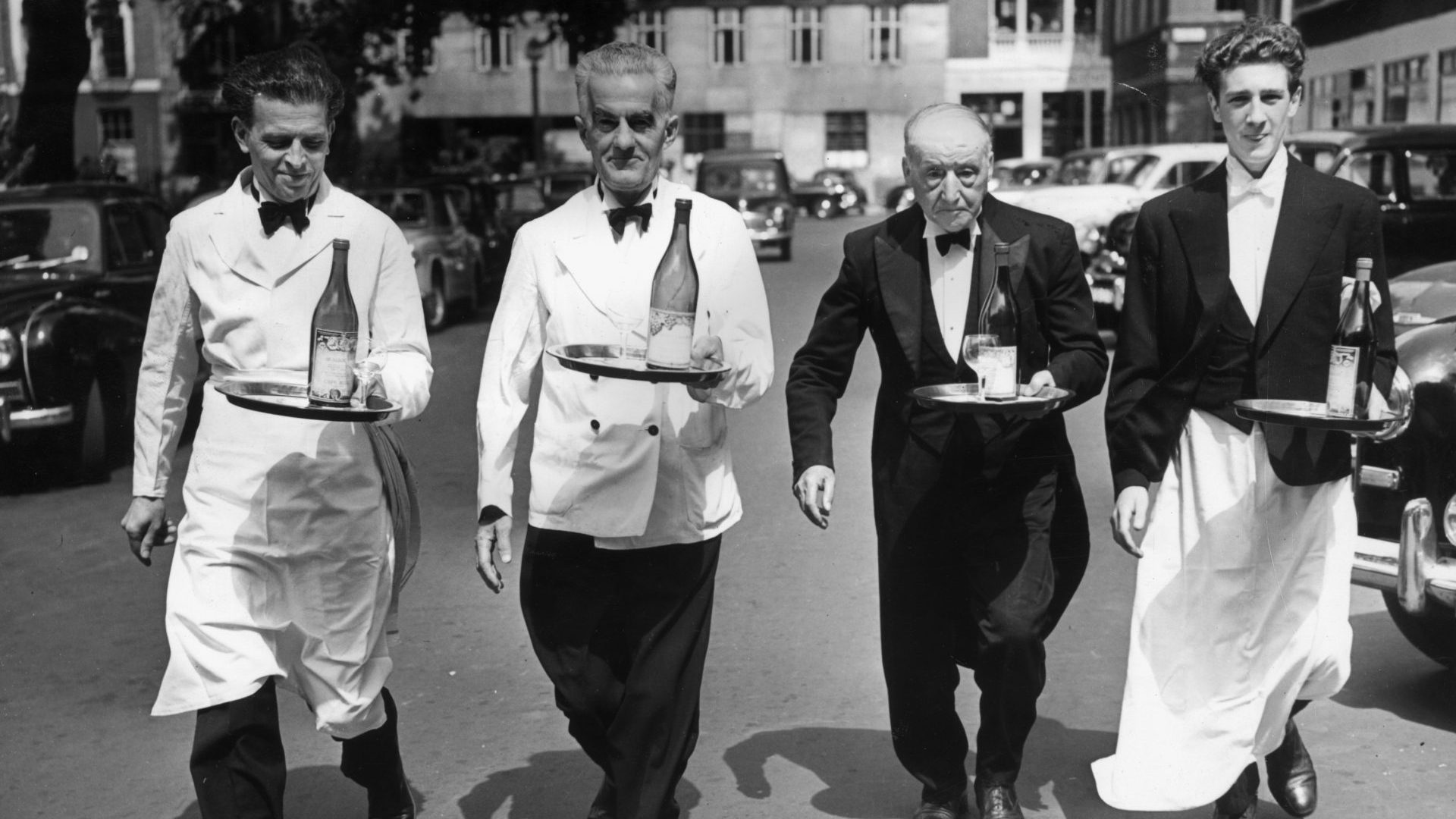 July 1955: Italian waiters in training for their annual race; carrying a half bottle of wine all the way from Soho Square to Greek Street without spilling a drop. Photo: Reg Speller/Fox Photos/Getty