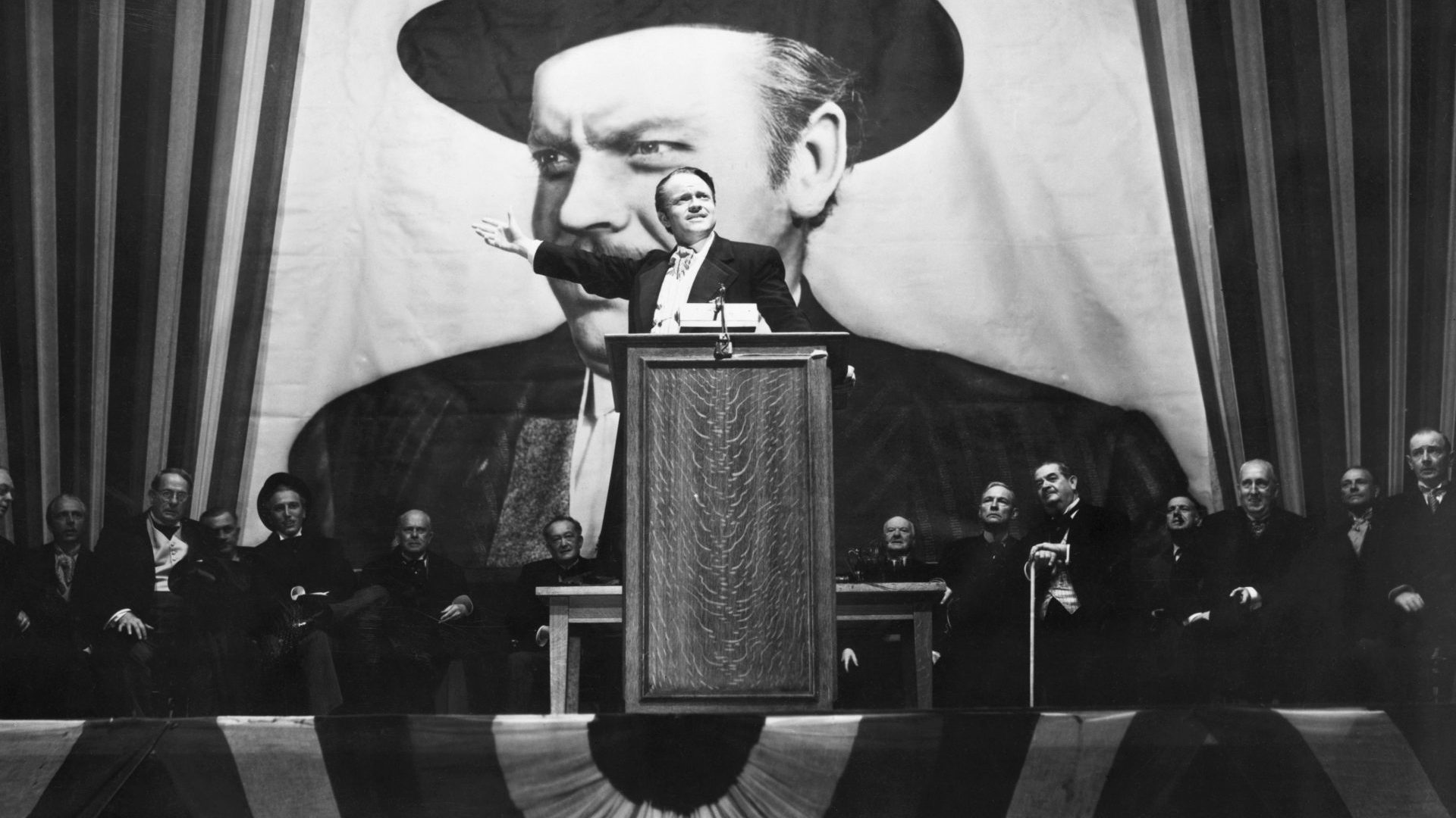 Charles Foster Kane (Orson Welles) makes a stirring campaign speech before a larger-than-life portrait of himself in a scene from Citizen Kane. Image: Bettmann