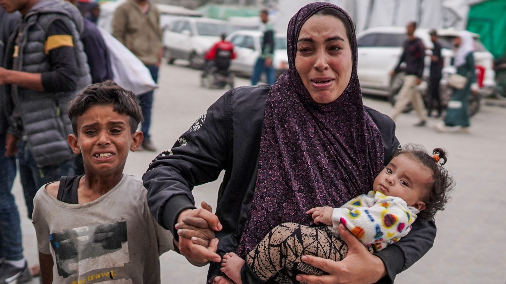 A Palestinian woman rushes her children to a hospital where casualties are brought in following Israeli bombardment in Bureij, Gaza. Photo: AFP/Getty