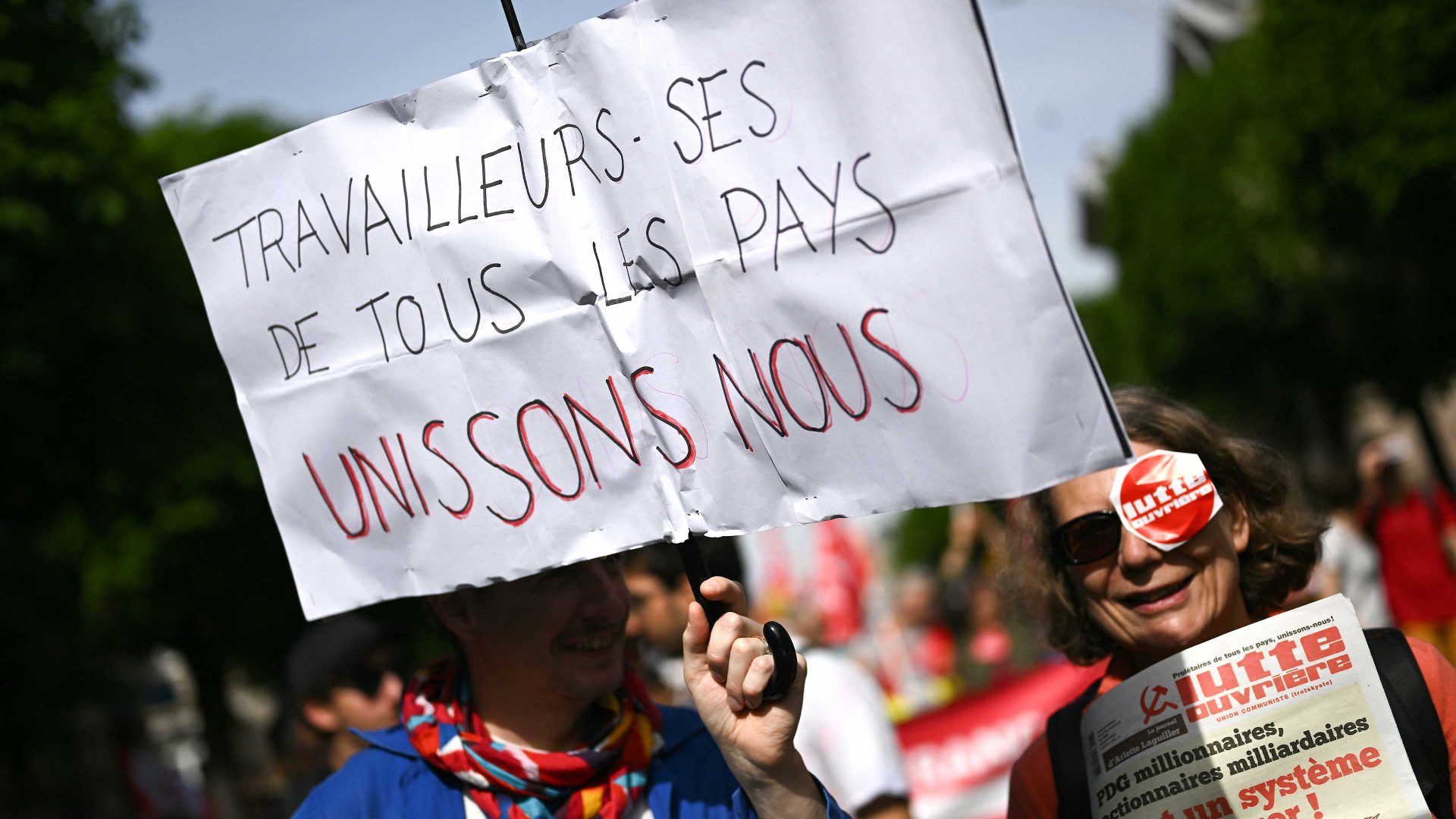 A protester holds a placard reading "Workers of the world, unite!" during a May Day (Labour Day) rally. Photo: SEBASTIEN BOZON/AFP via Getty Images