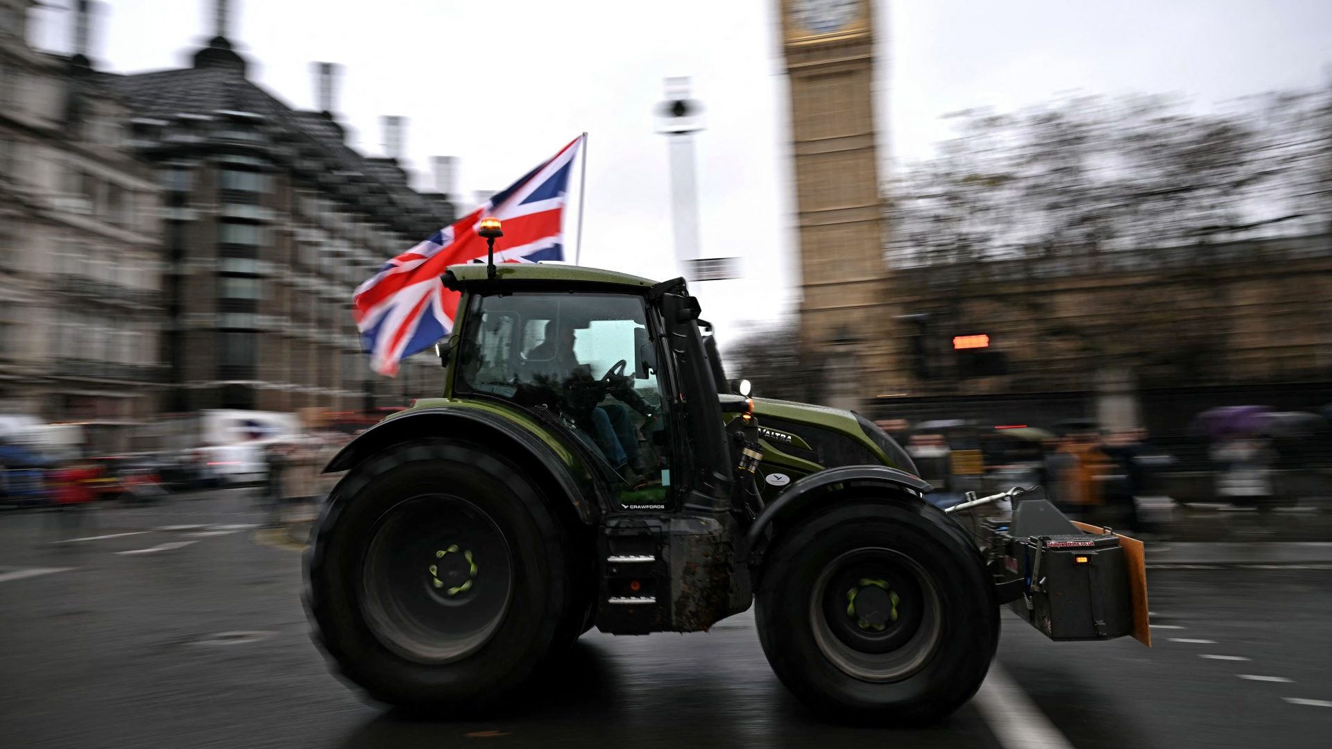 A farmer waves a Union flag as they drive a tractor past Big Ben (Photo by BEN STANSALL/AFP via Getty Images)