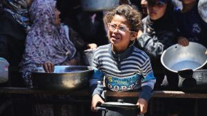 Palestinians wait in queues to receive food as the humanitarian crisis deepens due to closed border crossings and Israeli attacks in the al-Mawasi area in Khan Yunis, Gaza. Photo: Hani Alshaer/Anadolu/Getty